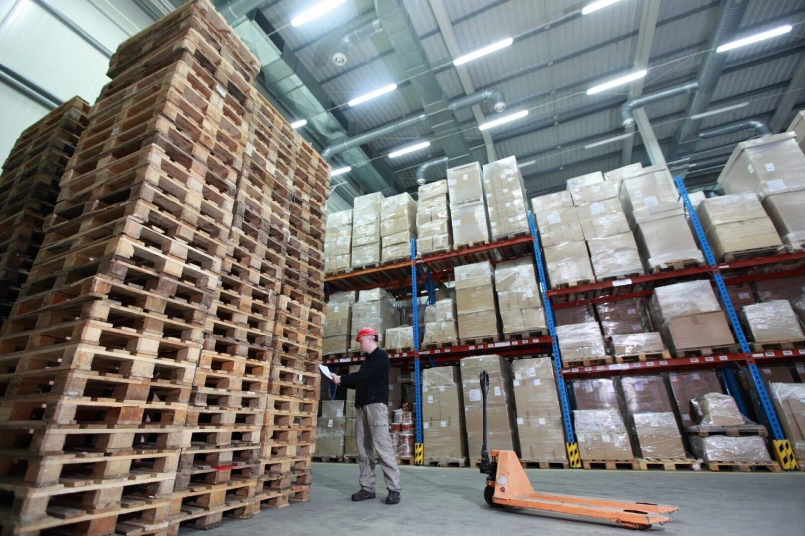 A man standing in front of stacks of pallets.