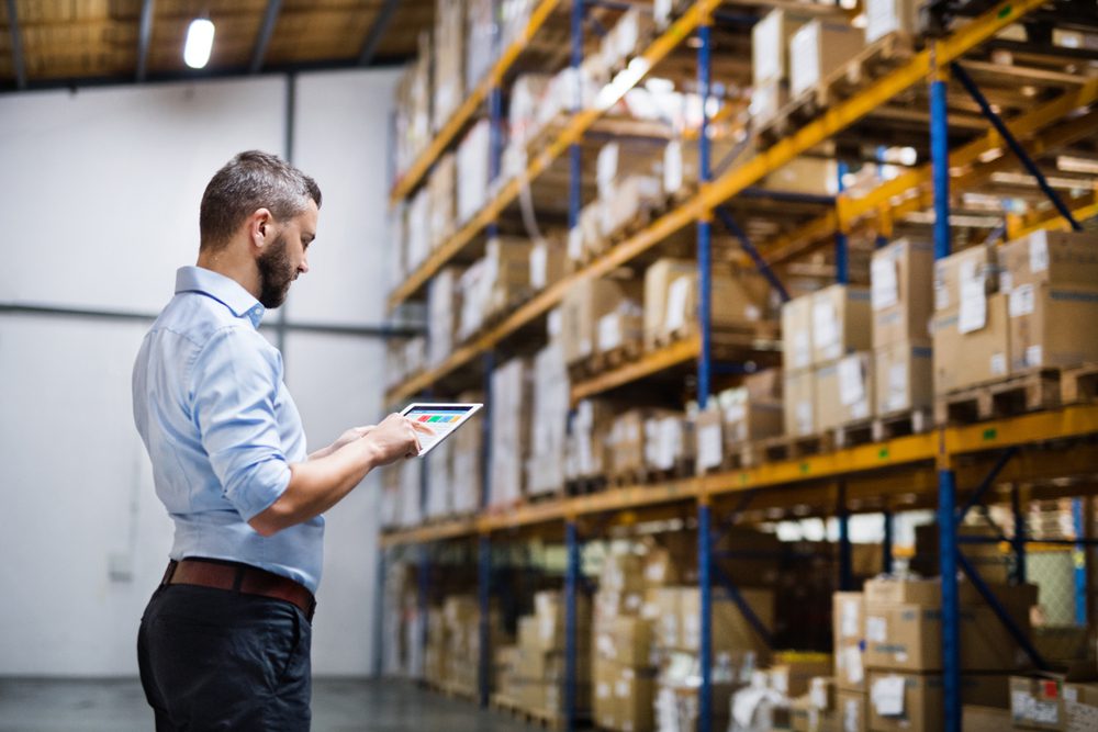 A man in a warehouse holding a tablet.